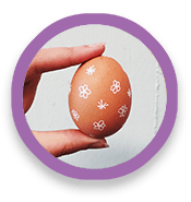 Hand holds egg decorated with drawings of flowers and stars.