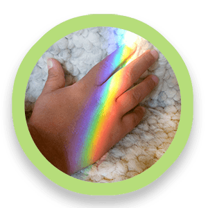 Rainbow light falls on the back of a person's hand.