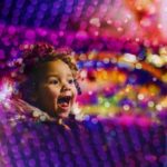 Child laughing, surrounded by colored lights