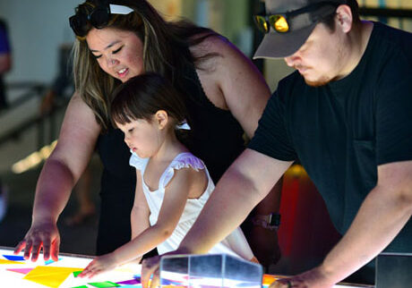 membership-family-3 Adults and child play with tabletop science exhibit at CuriOdyssey.